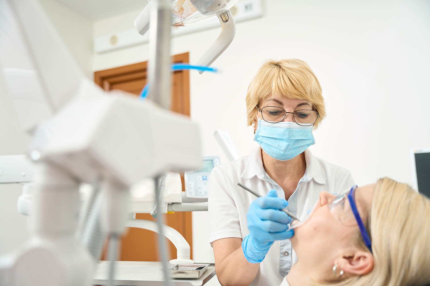 Woman dentist wearing a protective mask treats her teeth